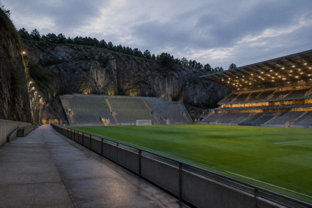 Evening light over a stadium pitch with empty stands before a match