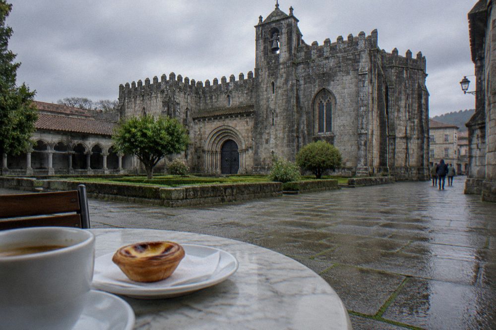 A traditional Portuguese cafe interior with marble tables and pastries displayed in a glass counter