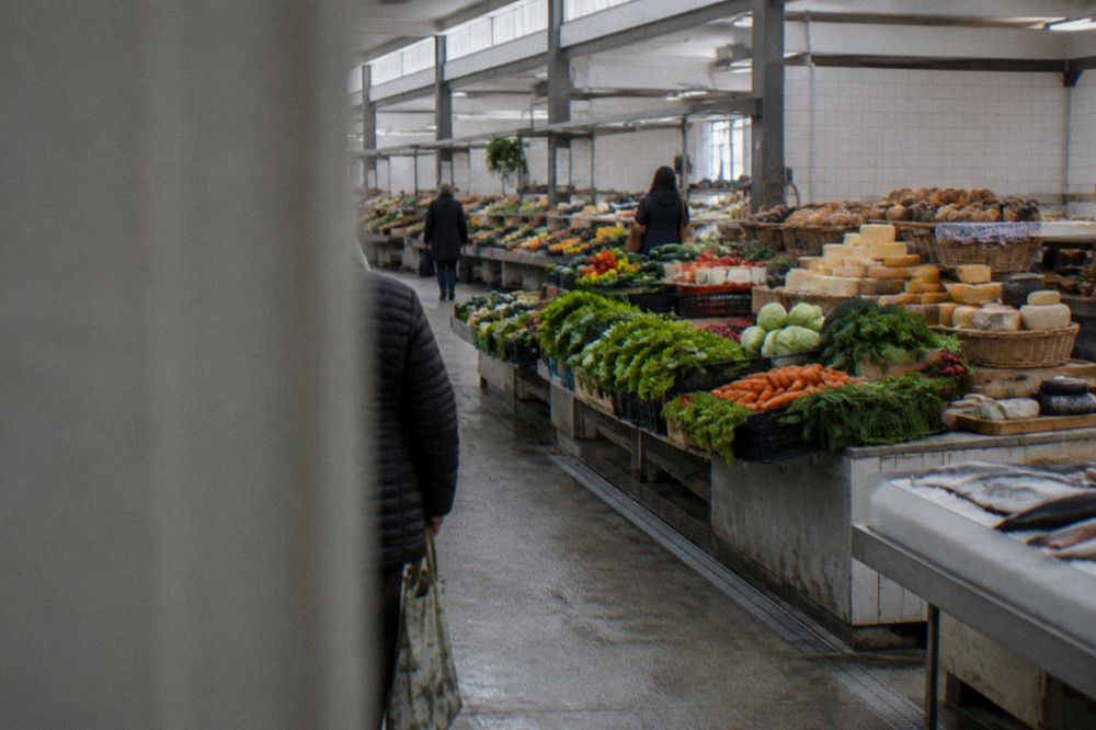 A covered market hall with stalls of vegetables, fish and cheese