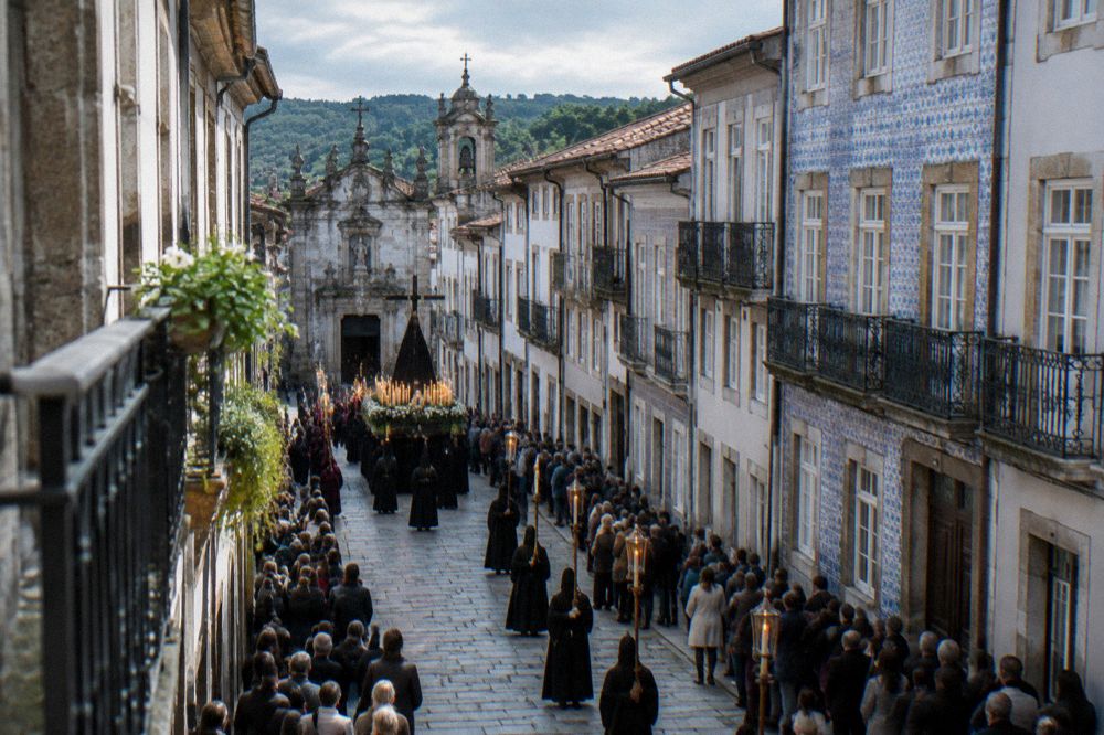 Crowds watching a candlelit religious procession in a narrow street of Braga during Holy Week