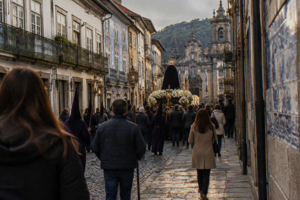 A procession crowd moving through a decorated Braga street during Holy Week