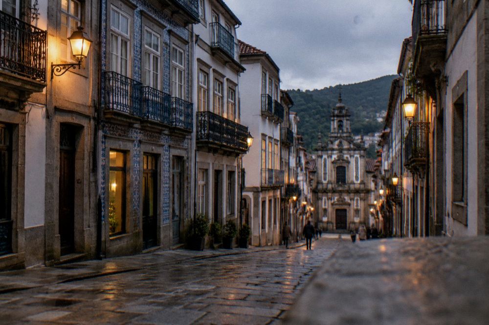 A lamplit street of old townhouses in central Braga in the early evening