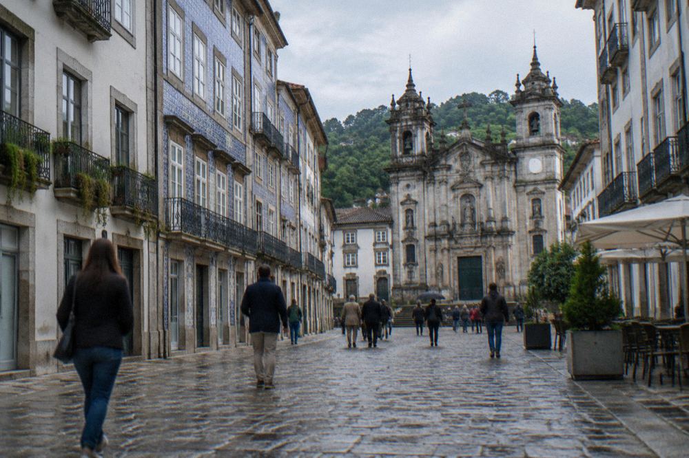 Visitors walking across a cobbled square lined with granite buildings in Braga's historic centre