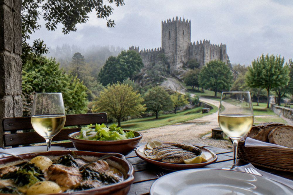A table set with plates of regional Minho food and glasses of white vinho verde wine