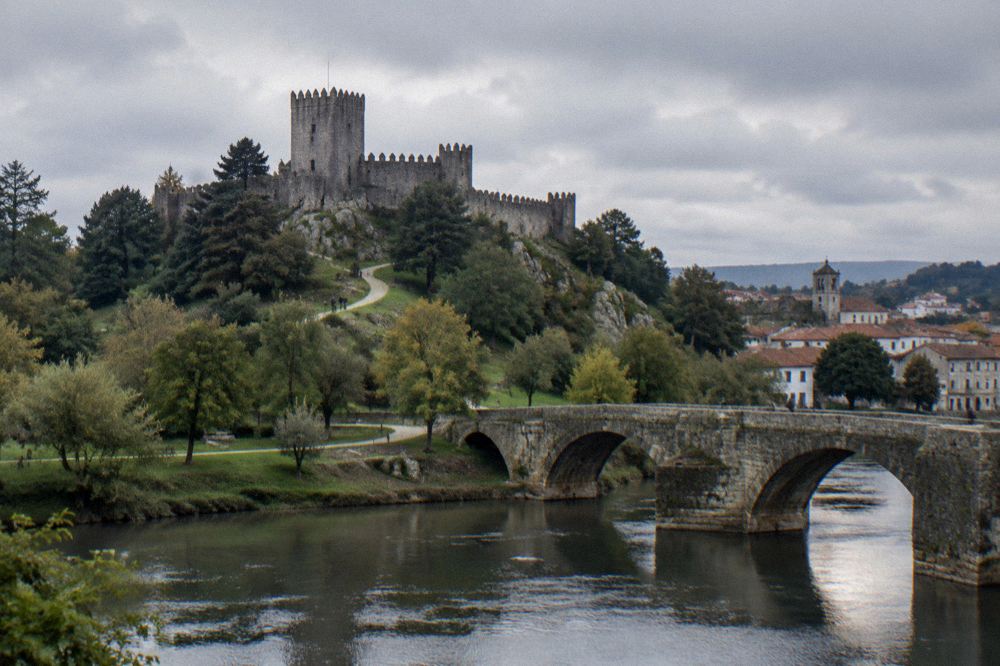 A stone bridge over a river in the Minho countryside with a small historic town beyond