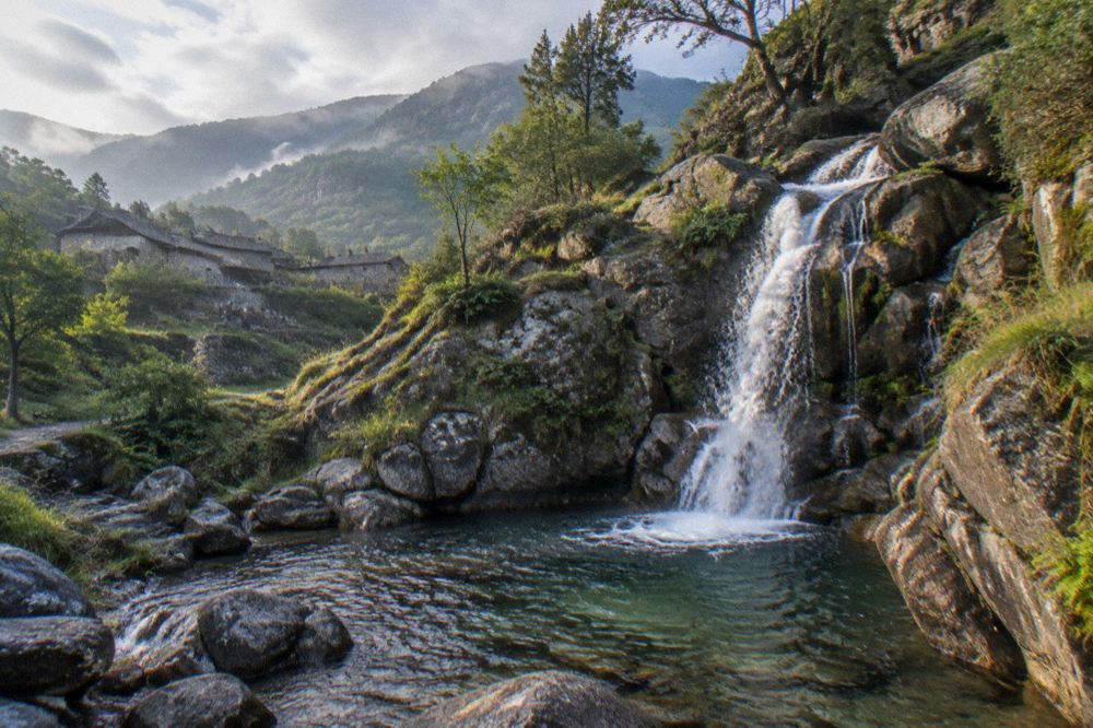 A mountain waterfall cascading into a clear pool among granite rocks in the Peneda-Geres national park