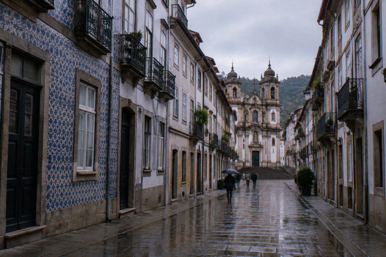 Wet cobblestone street in Braga's historic centre with reflections in the puddles and baroque facades along the row