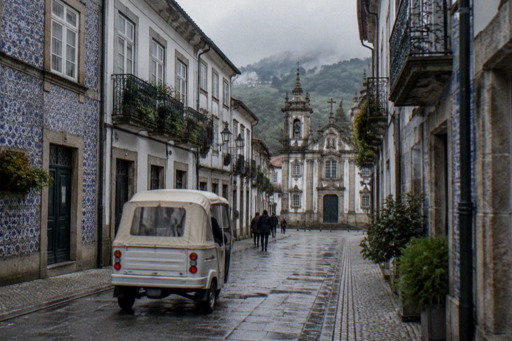 A tuk tuk passing baroque buildings on a street in central Braga